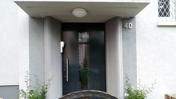 Een gevel met een nummer '40', een deur en een klein raam met metalen tralies.