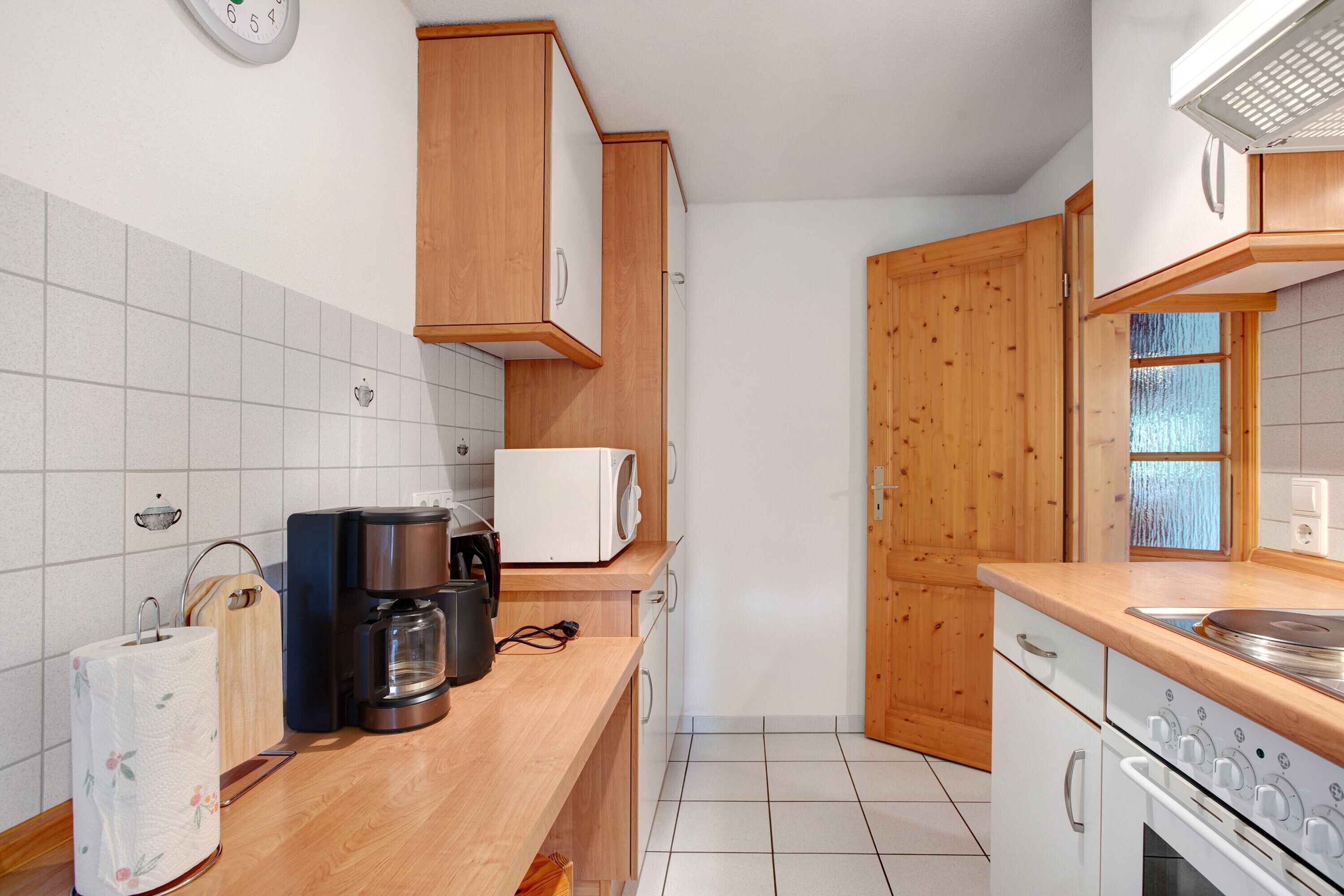 Une cuisine avec des meubles en bois, une machine à café, un four à micro-ondes et une cuisinière.