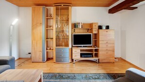 Een moderne woonkamer met een houten tv-meubel, een glazen kast en een flatscreen televisie.