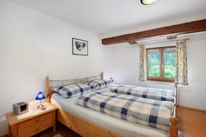 Une chambre à coucher avec un lit, une table de chevet, une lampe et une fenêtre avec des rideaux.