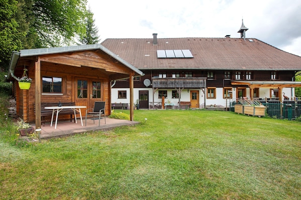 Une maison en bois dotée d’un patio couvert, d’un balcon et d’une cour clôturée.