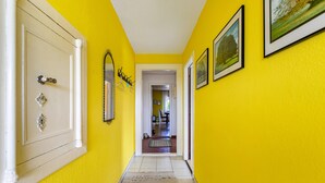 A hallway with yellow walls, a white door, and framed pictures on the wall. - Apartment 'Devich' with Private Terrace, Private Garden and Wi-Fi (Oersberg)