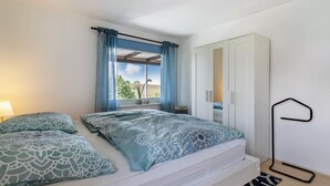 A bedroom with a bed, a wardrobe, a window with curtains, and a bedside lamp. - Apartment 'Devich' with Private Terrace, Private Garden and Wi-Fi (Oersberg)