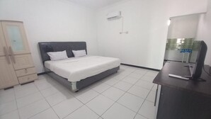 A bedroom with a bed, a desk, and an air conditioning unit. - Hotel O Penginapan Kryani (Long Kali)