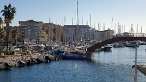 Una marina con numerose imbarcazioni ormeggiate, un ponte e edifici sullo sfondo.