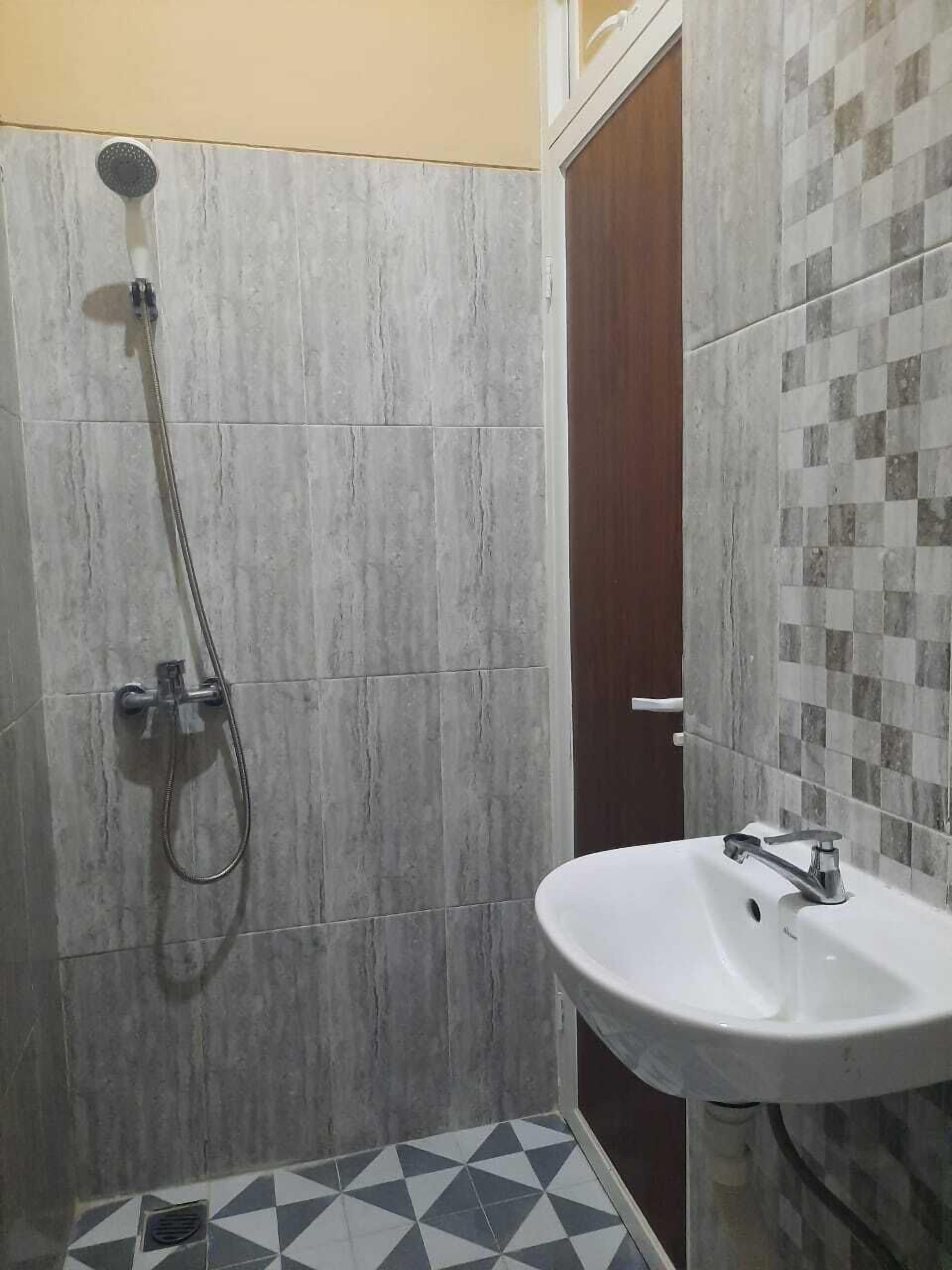 A bathroom with a shower, a sink, and a tiled floor.