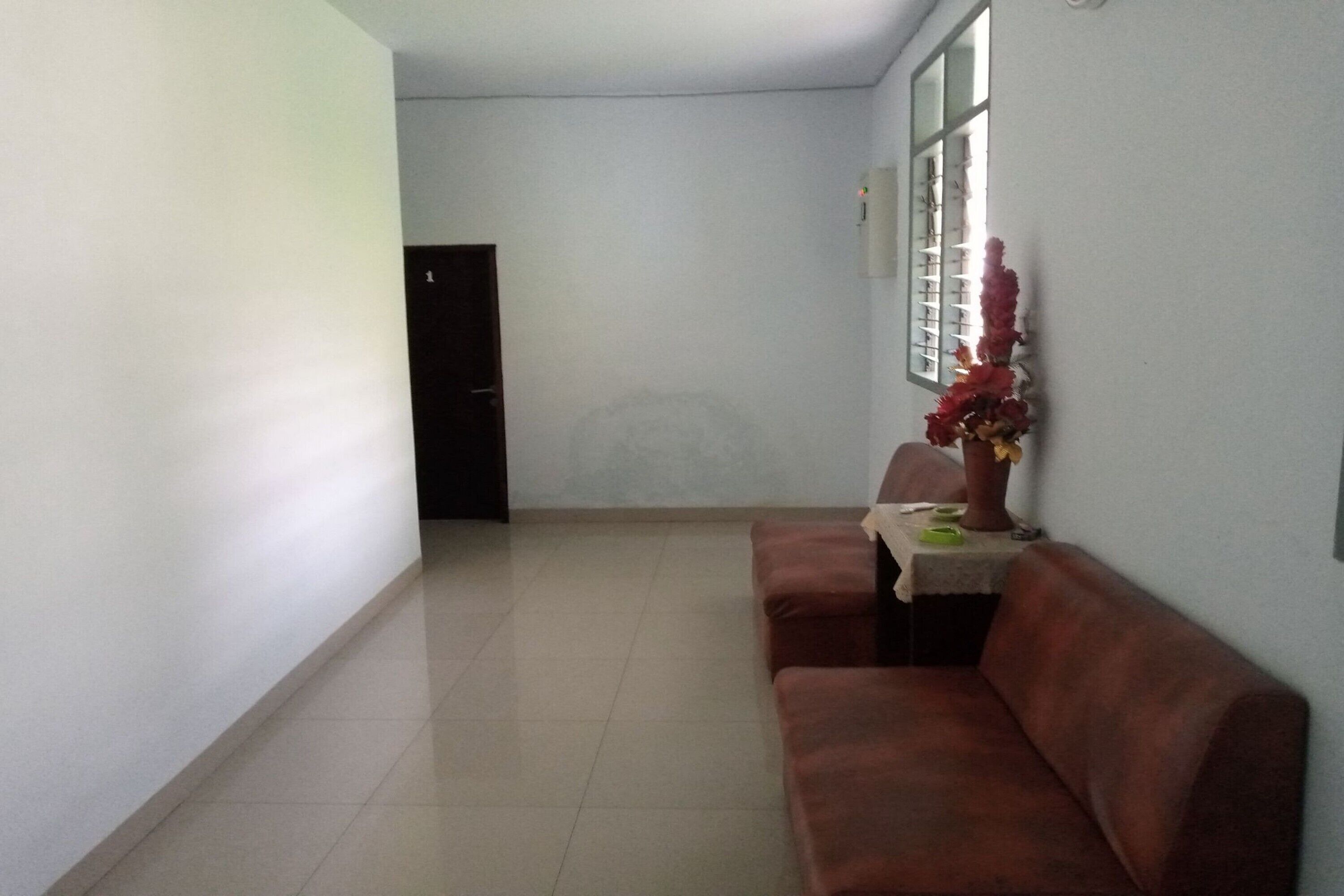A hallway with a brown couch, a potted plant, and a door at the end.