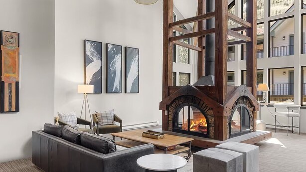Una sala de estar moderna con chimenea, sofá de cuero y obras de arte en la pared.