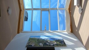 A room with a skylight, a painting of a landscape, and a wooden ceiling.
