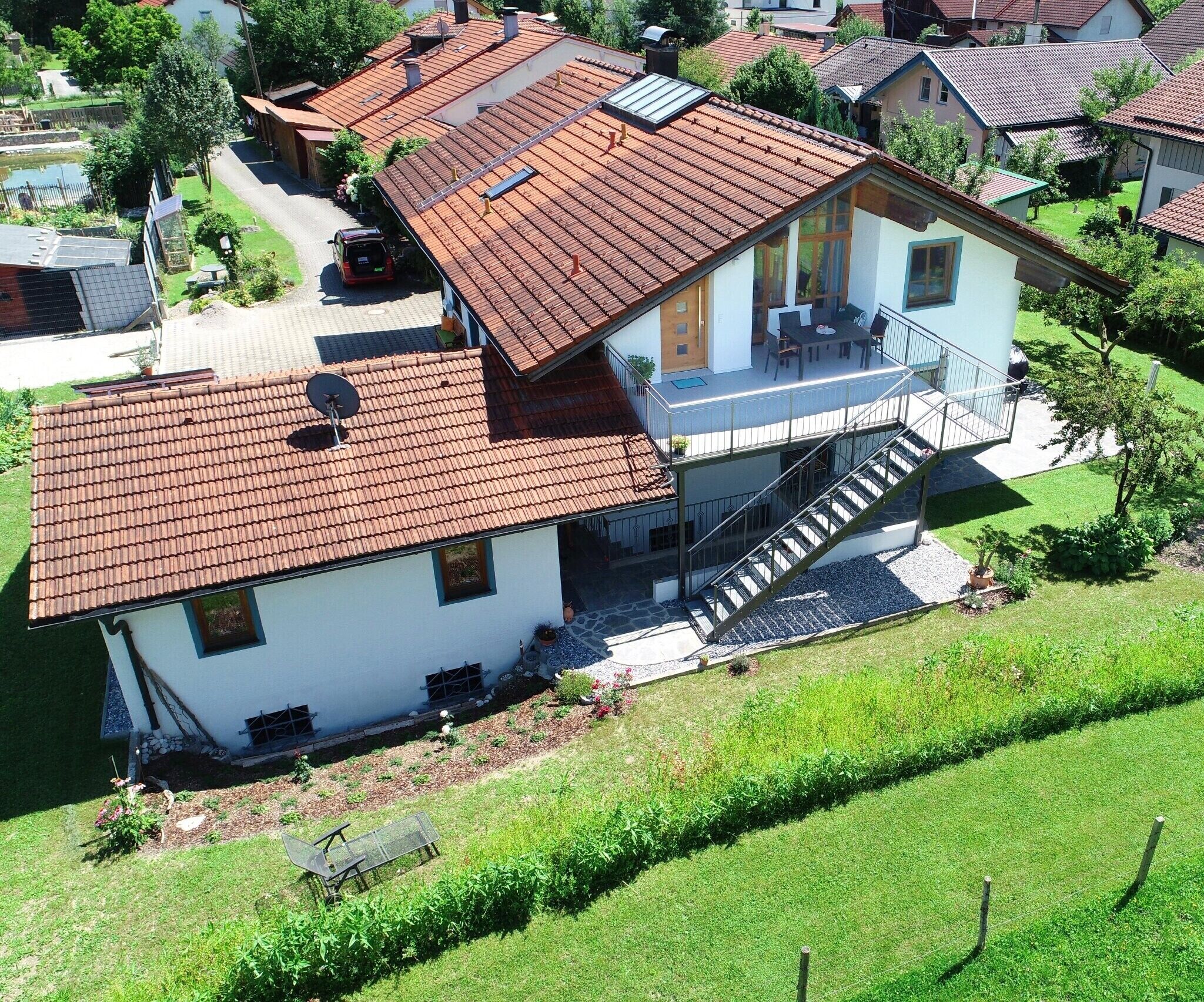 Ein zweigeschossiges Haus mit rotem Ziegeldach, einem Balkon und einer Treppe, die zum Obergeschoss führt.