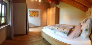 A bedroom with a wooden bed, a wardrobe, a door, and a window.