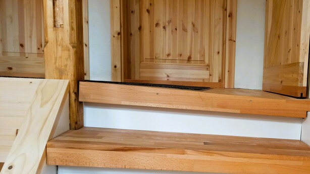 Eine Holztreppe mit schwarzer Handlauf und weißen Wänden.