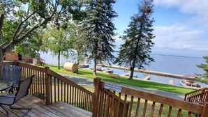 A wooden deck with outdoor seating, a view of the water, and a sign prohibiting charcoal grills.