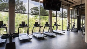 Et fitnesscenter med løbebånd, spinningcykler og boksebold, store vinduer og et plant gulv.