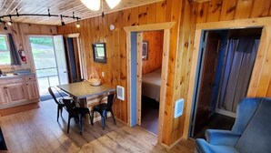 Een gezellig interieur van een blokhut met een houten eethoek, een bank en een keuken met een spoelbak en kastjes.