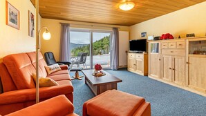 Una habitación con sofá, mesa, televisión y armario.