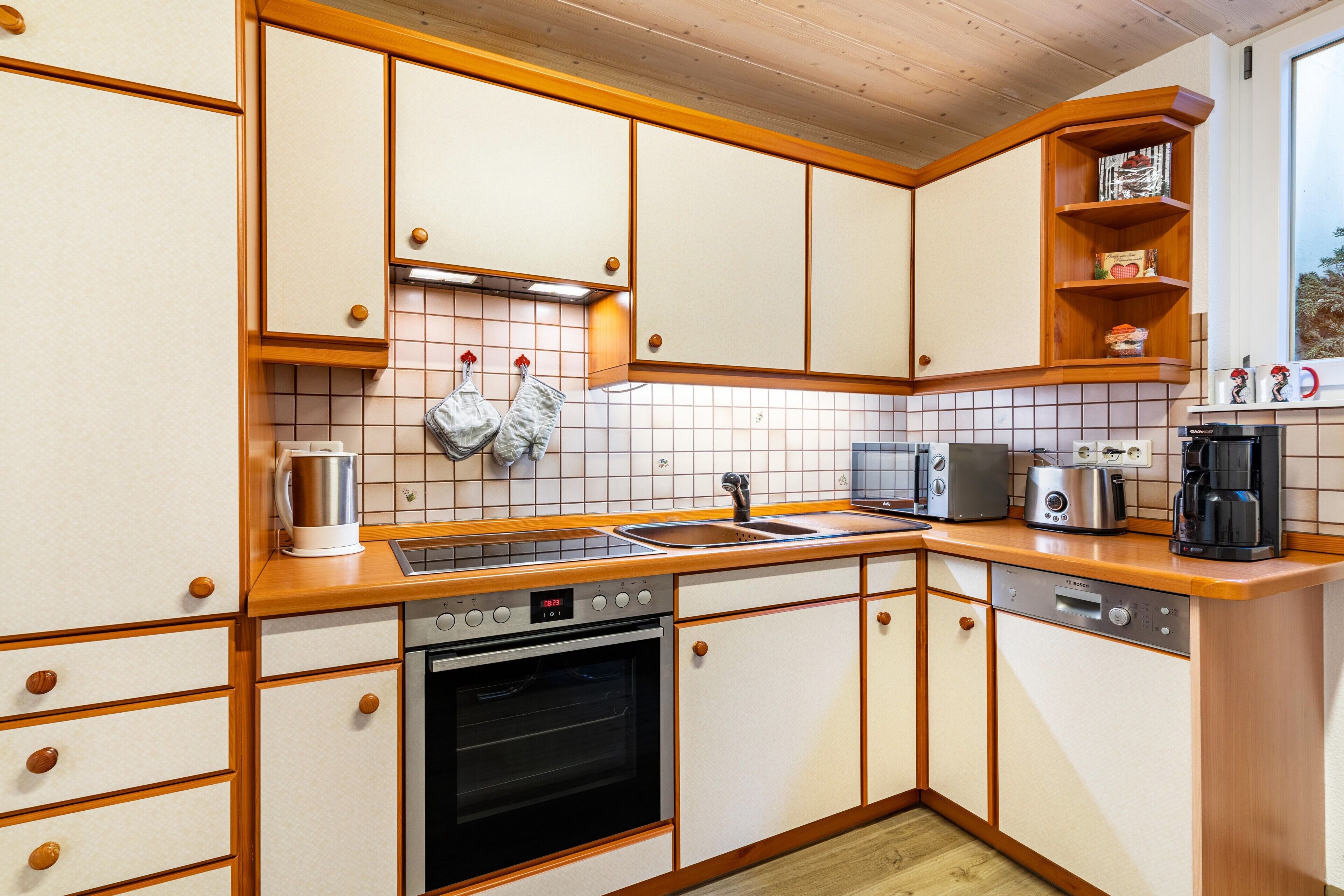 Una cocina con armarios de madera, horno empotrado, cafetera y tostadora.