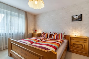 A bedroom with a wooden bed, a nightstand with a lamp, and a wall-mounted picture. - Apartment 'Berghansenhof' with Mountain View, Private Terrace and Wi-Fi (Wolfach)