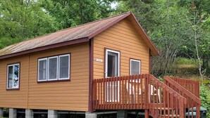 A wooden cabin with a porch and a staircase leading to a door marked "Sunset".