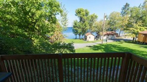 A wooden deck with a view of a lake and a small building in the background.