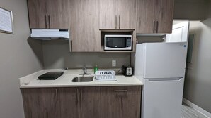 Une cuisine de taille réduite, dotée de meubles en bois, d’un four à micro-ondes, d’un grille-pain et d’un réfrigérateur.