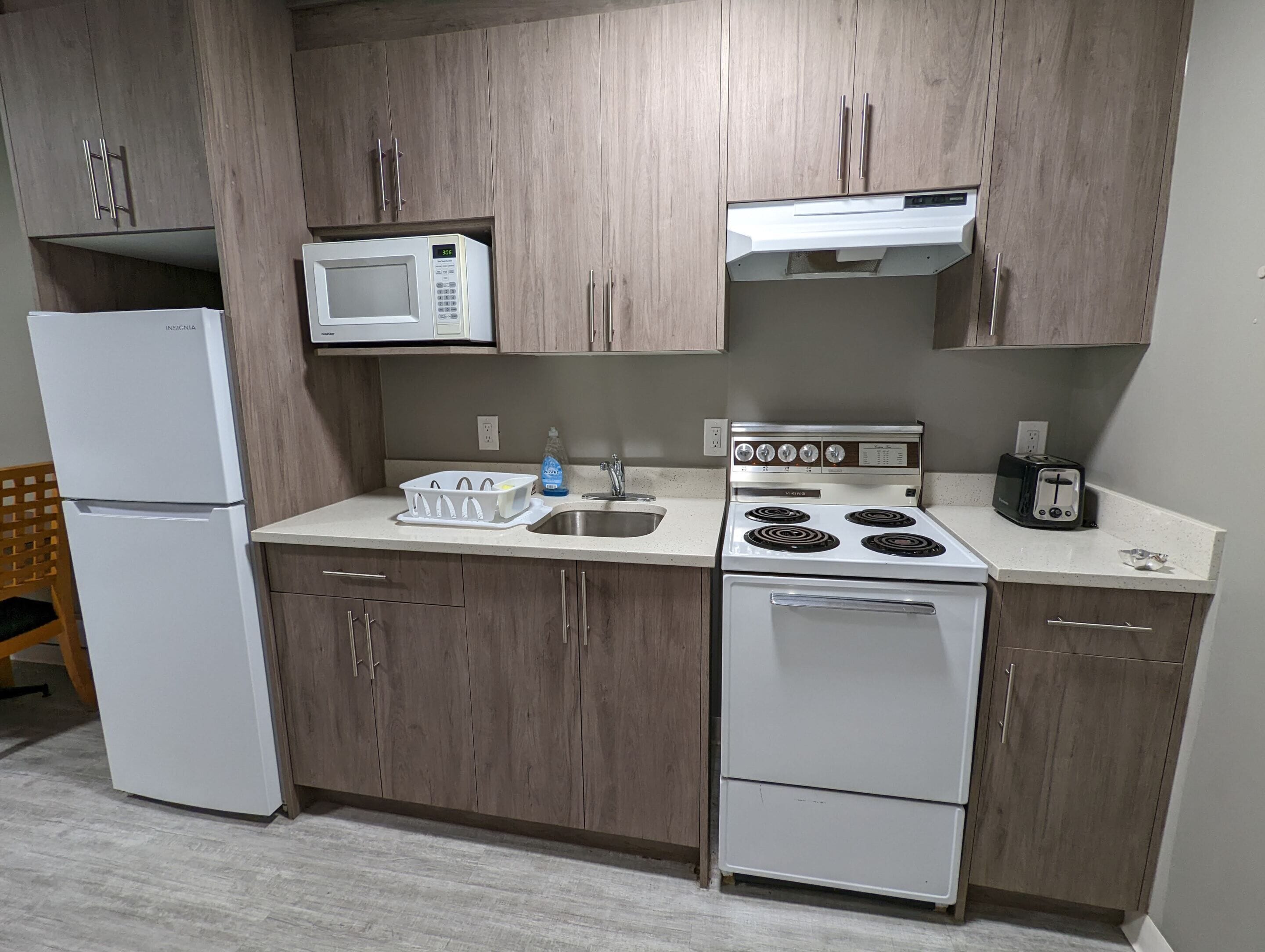 Una cocina con armarios de madera, un refrigerador blanco, un microondas, una estufa y un tostador.