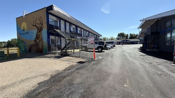 A motel with a mural of a deer, a fenced parking area, and a building with multiple windows.