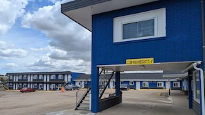 A blue building with a yellow sign indicating a maximum height of 2.23 meters. - Riverside Motel & Suites (Medicine Hat)