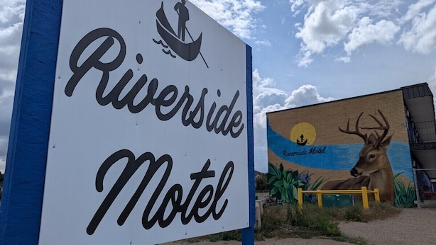 A sign for Riverside Motel with a canoe and a deer illustration. - Riverside Motel & Suites (Medicine Hat)