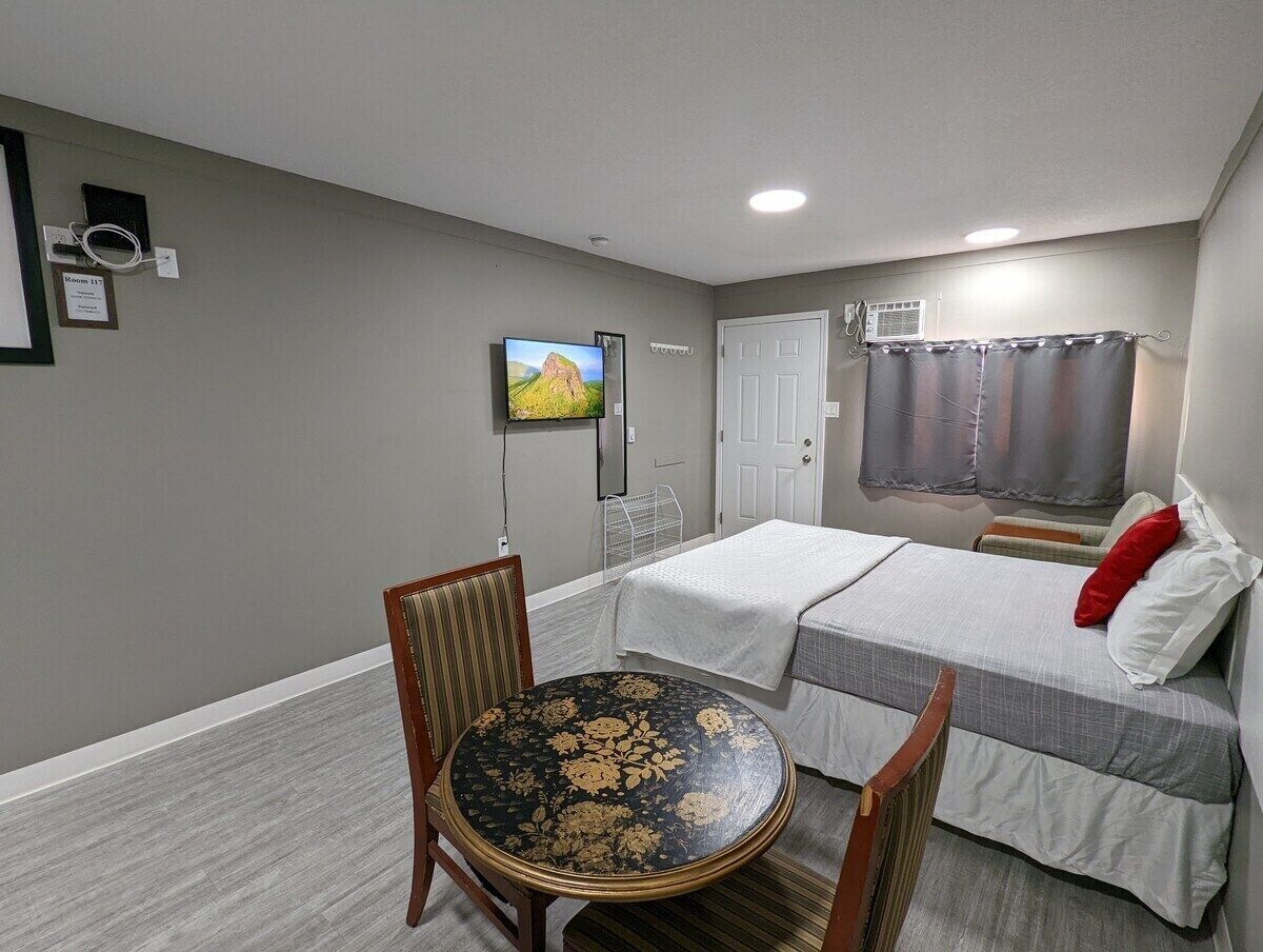 A room with two beds, a TV, a table, and a chair.