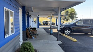 Un motel doté d’un parking couvert, d’un petit jardin et d’une façade bleue.
