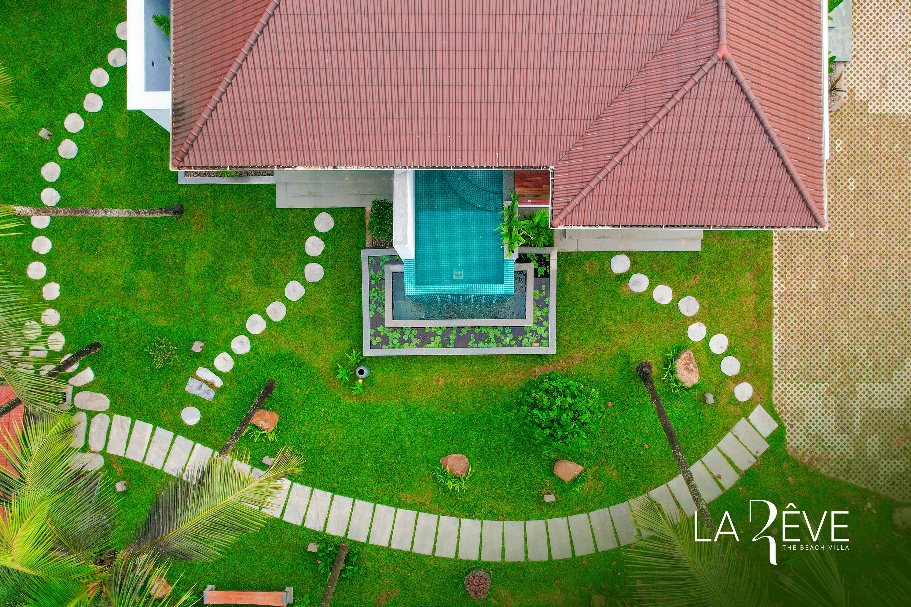 Eine Vogelperspektive auf eine Villa mit Swimmingpool, umgeben von einem gepflegten Garten und einem Kiesweg.