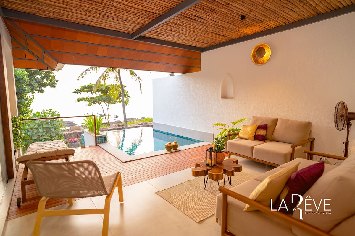 A modern villa with a pool, outdoor seating, and a view of the surrounding landscape.