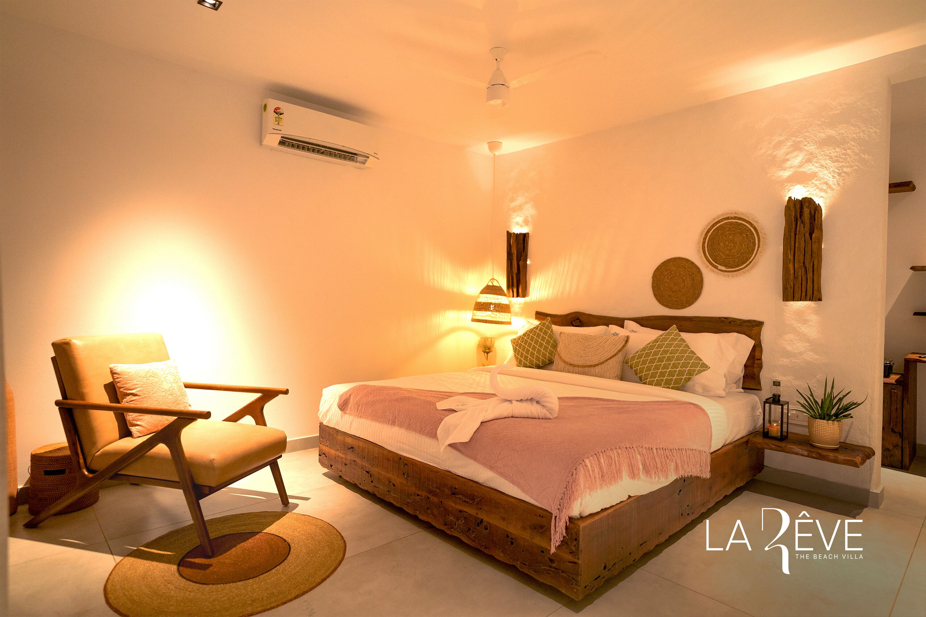 Un dormitorio con una cama de madera, una silla, una lámpara y un aire acondicionado instalado en la pared.