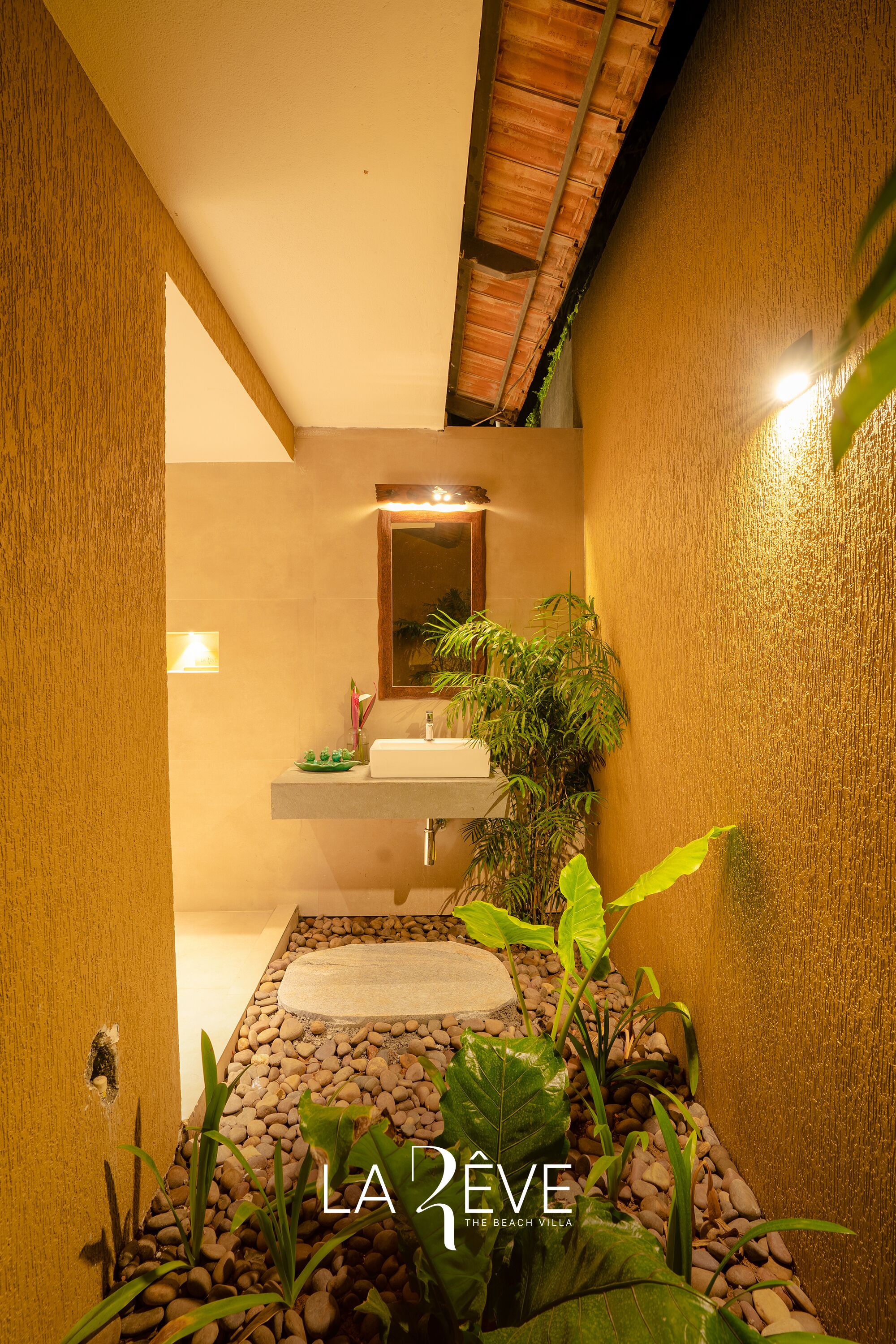 A bathroom with a sink, mirror, and plants.