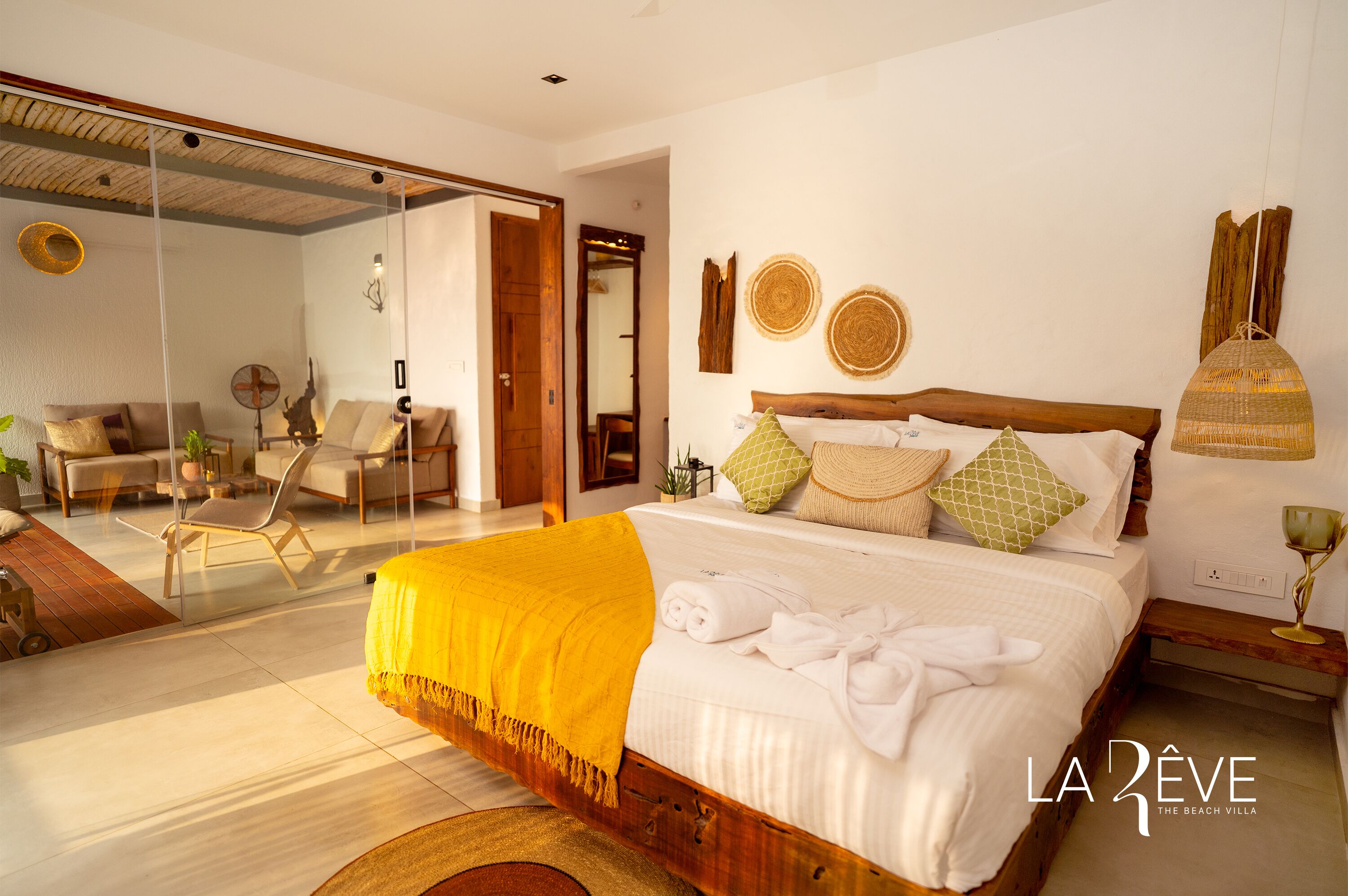 A spacious bedroom with a large bed, a wooden headboard, and a bright yellow throw blanket.