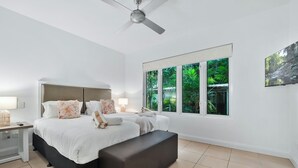 A bedroom with a large bed, a bench, a ceiling fan, and a window with a view of greenery. - 2 Bedroom Ground Floor Pool Access Apartment 5113/4 (Palm Cove)