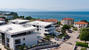 Una zona residencial moderna con edificios blancos, una piscina y vistas al mar.