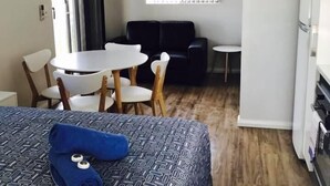 A hotel room with a bed, a dining table with chairs, a sofa, and a refrigerator. - Tasman Holiday Parks - Ledge Point (Ledge Point)