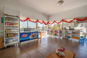 A spacious indoor area with a refrigerated display case on the left, a counter with a 'Drumstick' sign, and shelves stocked with various items. - Tasman Holiday Parks - Ledge Point (Ledge Point)