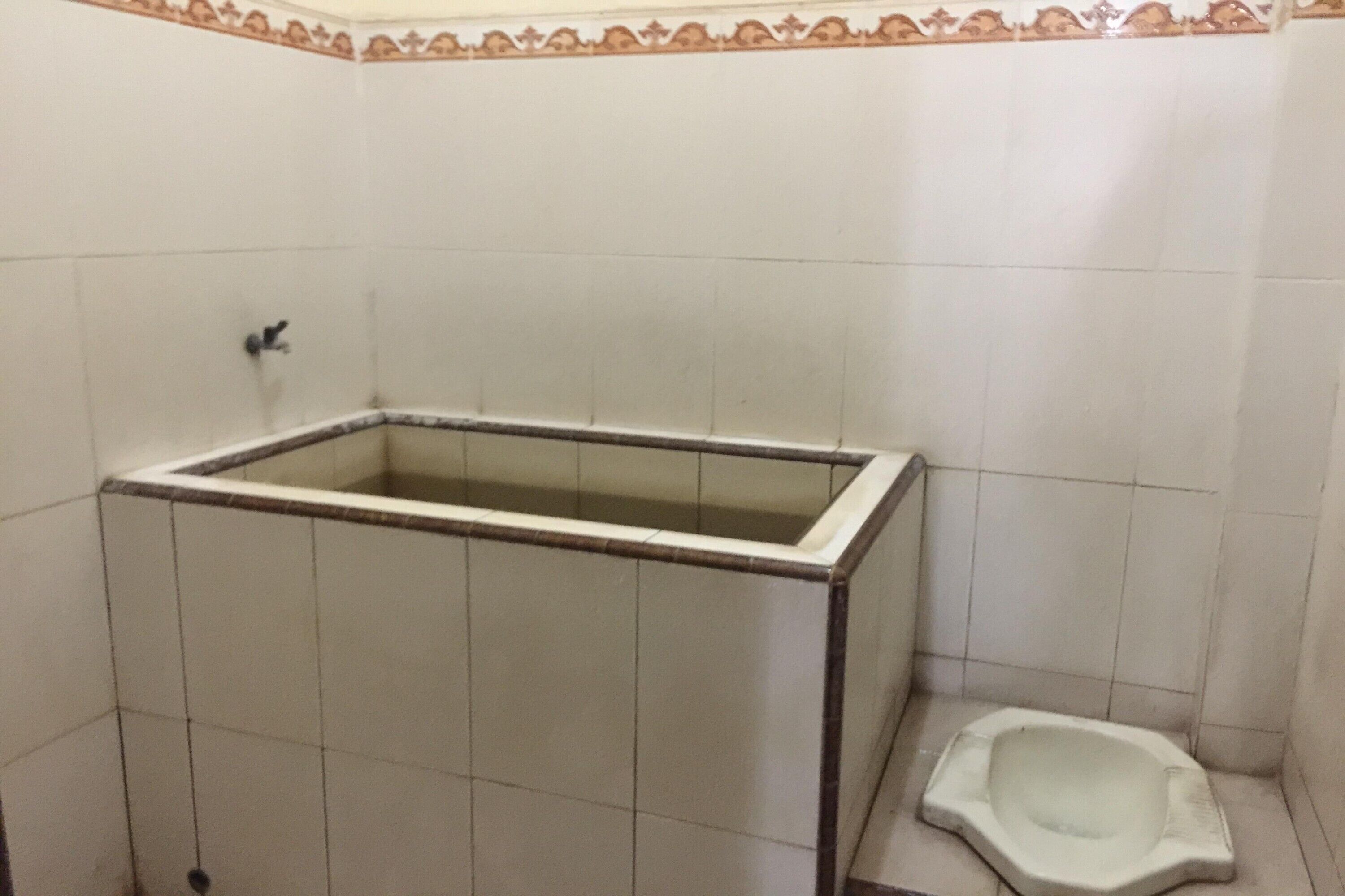 A small bathroom with a bathtub and a squat toilet.