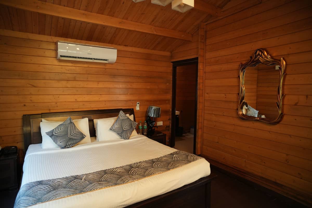 A wooden-paneled bedroom with a bed, pillows, a mirror, and an air conditioning unit.