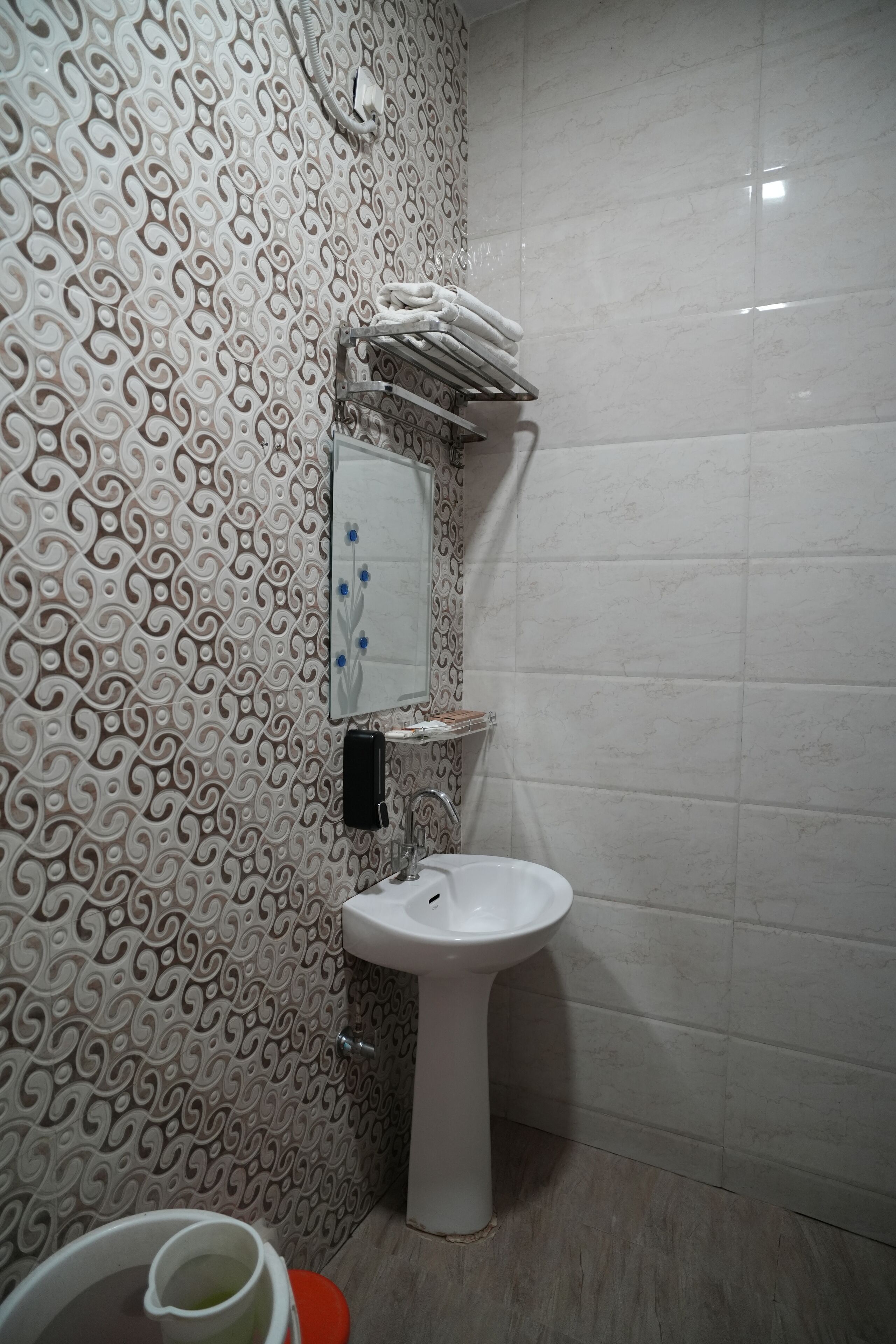 A bathroom with a patterned wall, a toilet, a sink, and a mirror.