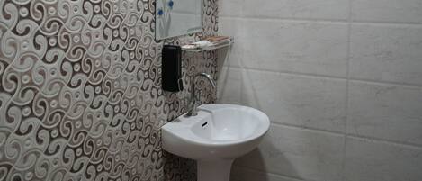 A bathroom with a patterned wall, a toilet, a sink, and a mirror.