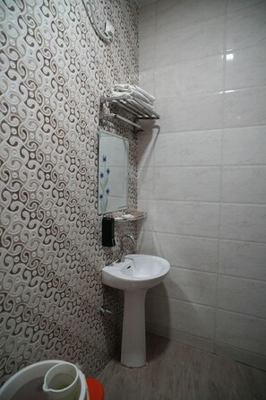 A bathroom with a patterned wall, a toilet, a sink, and a mirror. - Naman Bagh (Alwar)