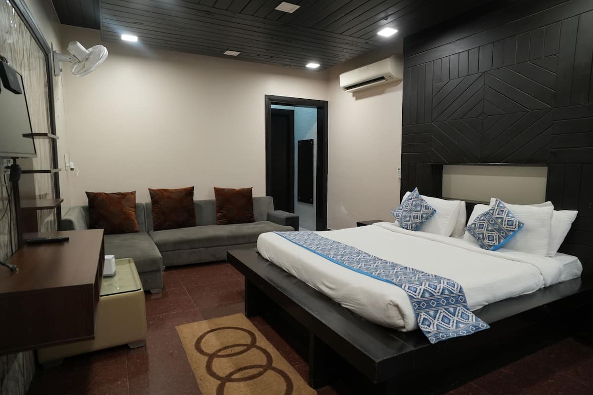 A modern hotel room with a bed, a sofa, a desk, and a mirror.