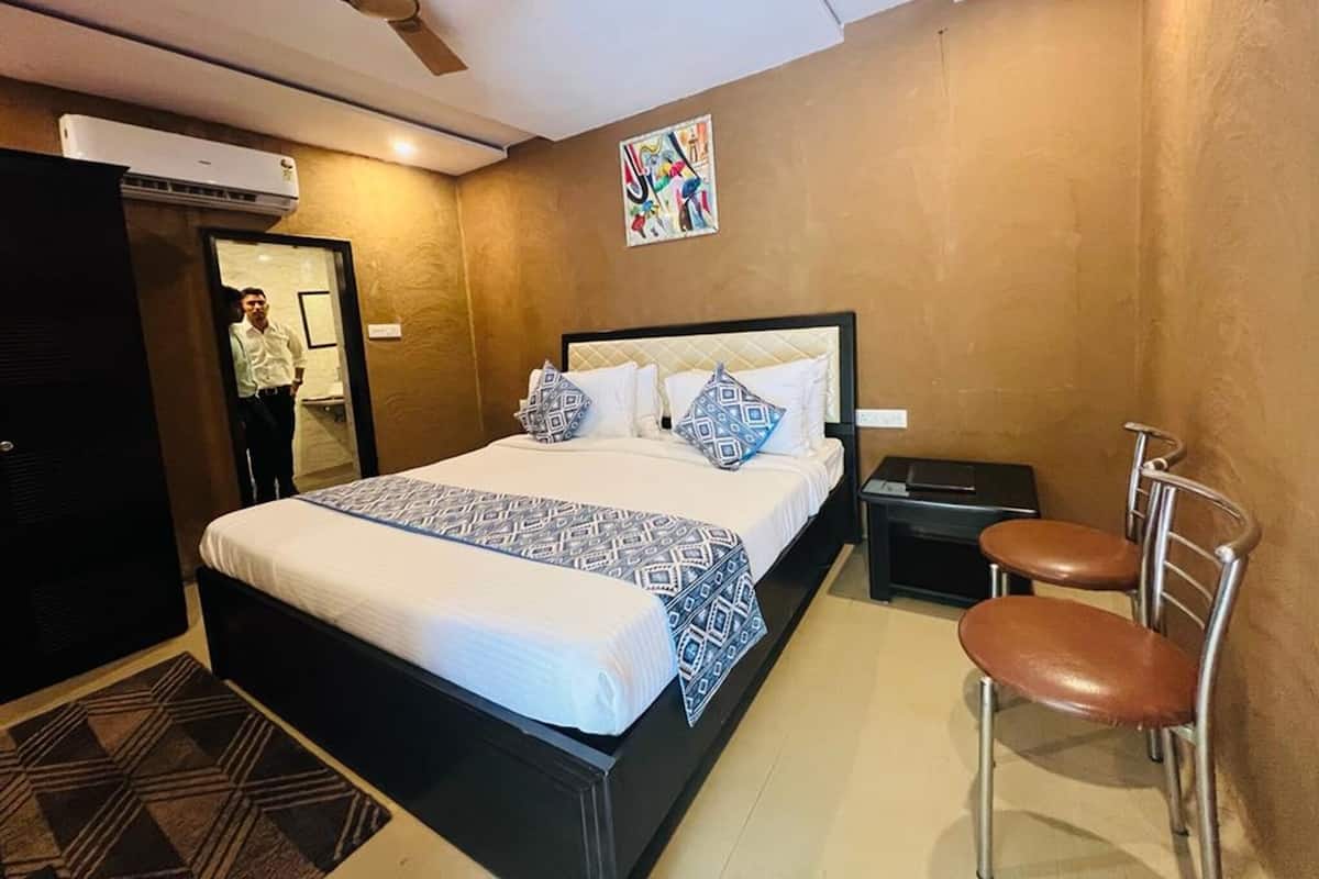 A hotel room with a bed, a chair, a nightstand, an air conditioning unit, and a ceiling fan.