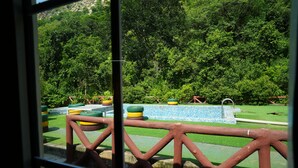 Vista de un parque con una cerca de madera, una fuente y una piscina con azulejos azules.