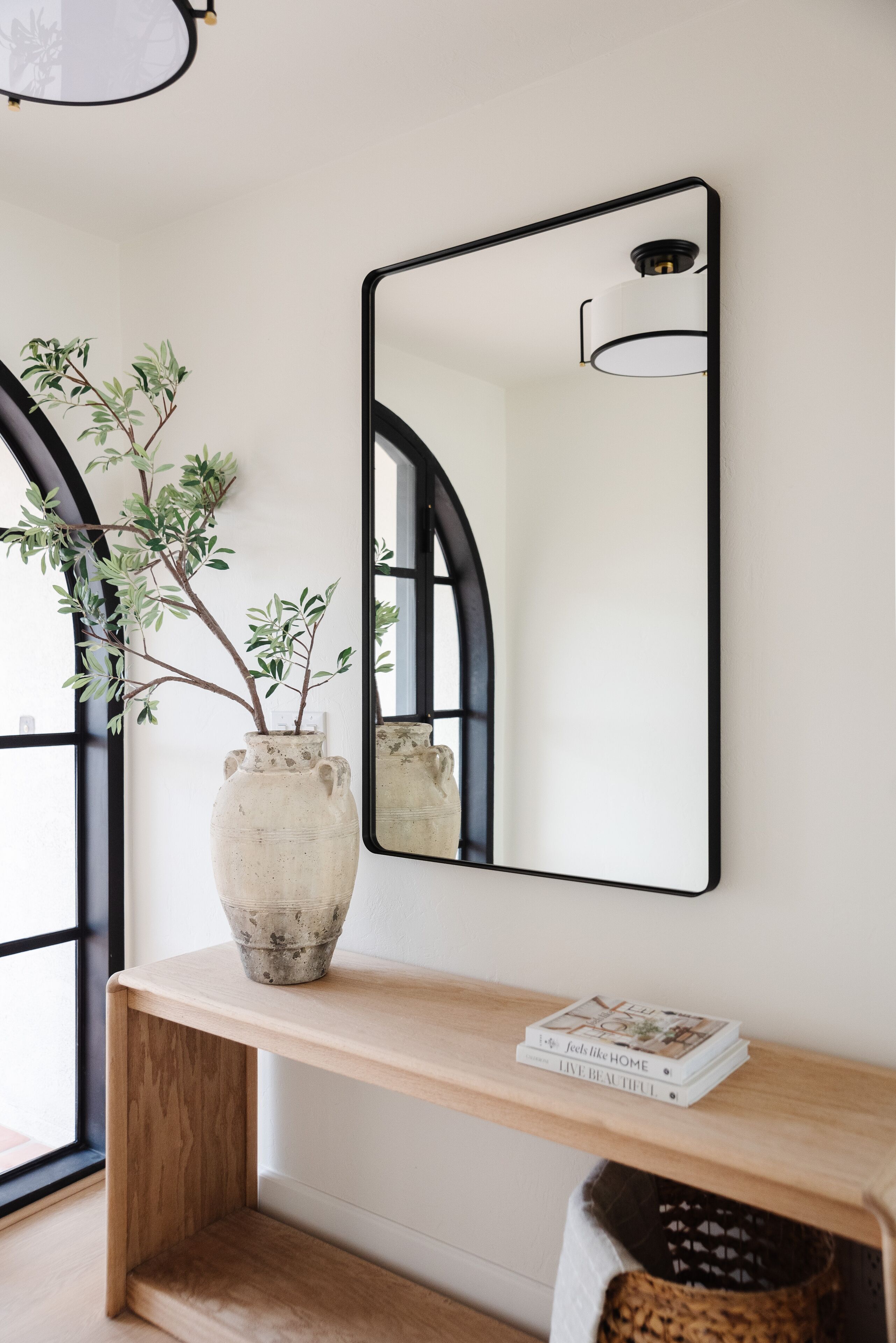 A wooden console table with a white vase and a mirror.