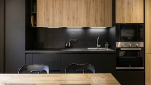 A modern kitchen with black cabinets, a wooden ceiling, and a Bosch oven. - Vouvy - Moderne 4pax | Remontée Flégère 5min | Praz | Arve (Chamonix-Mont-Blanc)